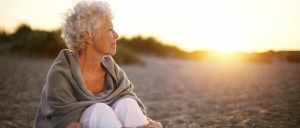 Old woman sitting on the beach looking away at copyspace. Senior female sitting outdoors